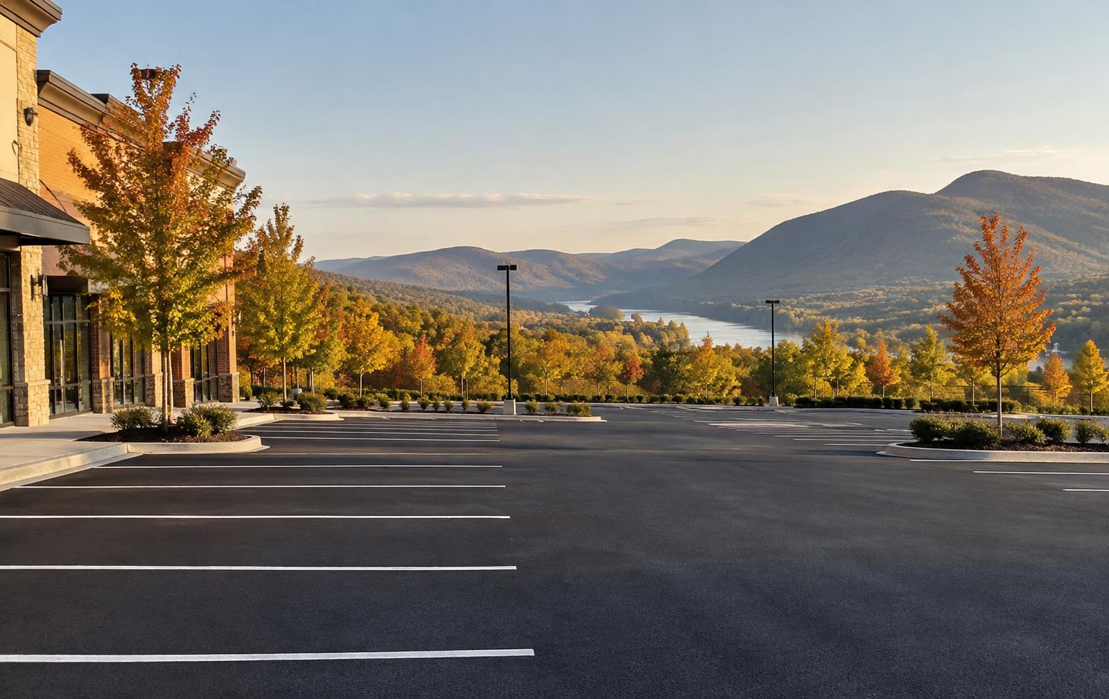 Fresh black asphalt commercial parking lot with white striping, Hudson Valley mountains and river behind